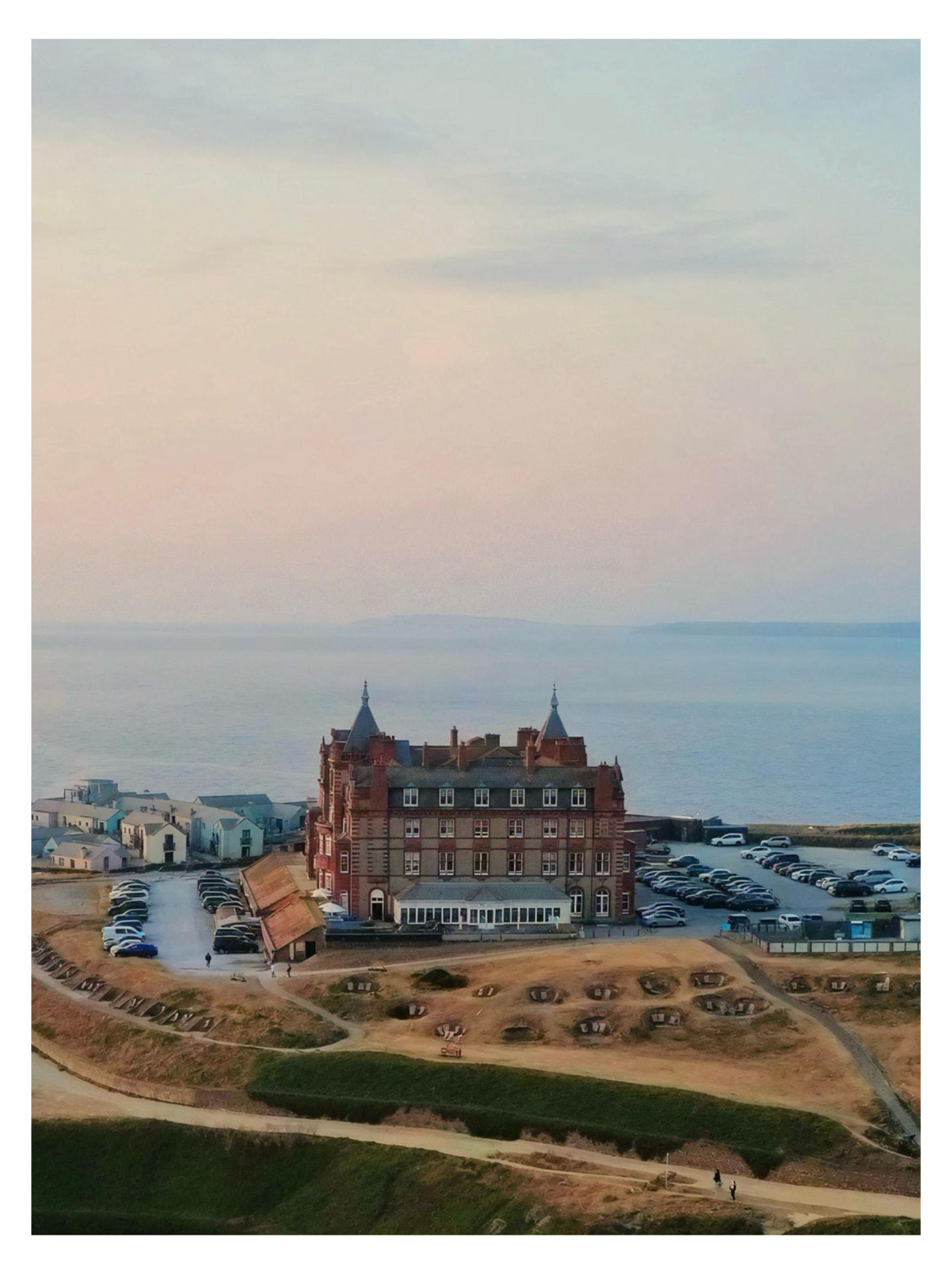 Aerial view of a clifftop hotel above the sea at dusk